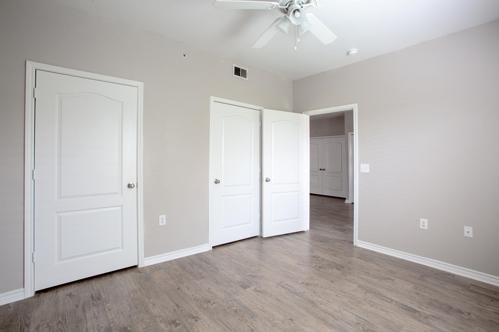 A room with a ceiling fan and three doors.