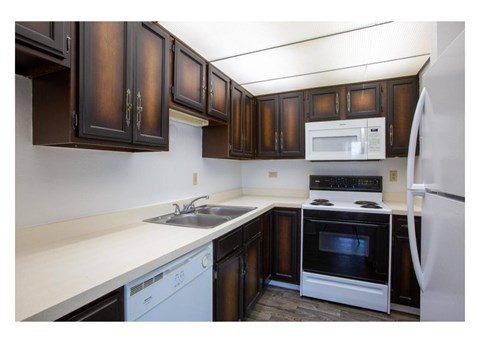 A kitchen with brown cabinets and white appliances.