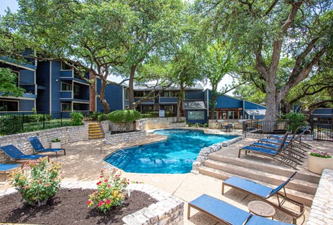 A pool surrounded by trees and chairs.