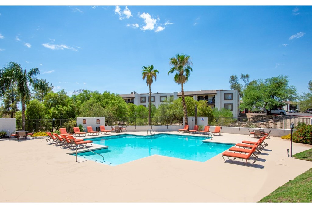 A pool with chairs and a building in the background.