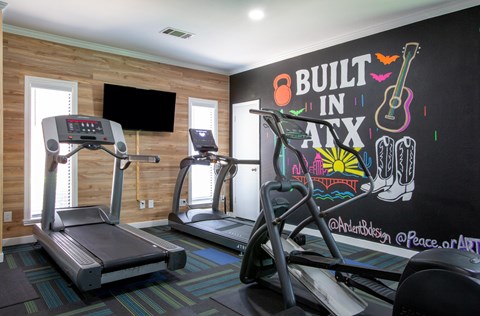 A gym with treadmills and a chalkboard wall that says "Built in Nate".