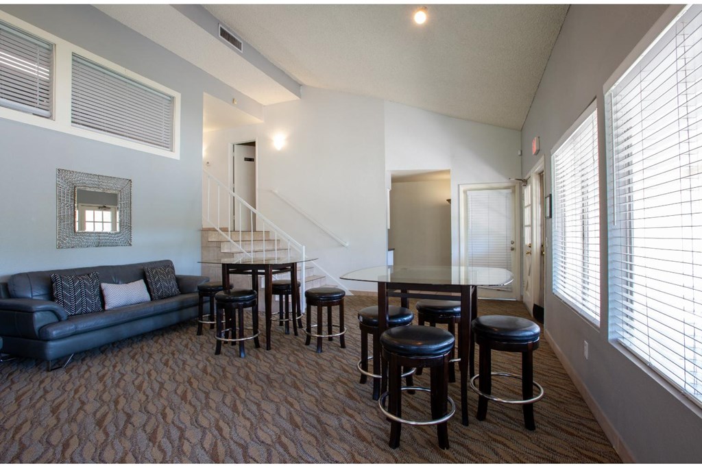 A living room with a couch, chairs, and a staircase.