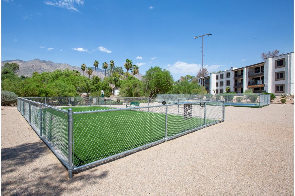 A tennis court surrounded by a fence with a mountain in the background.