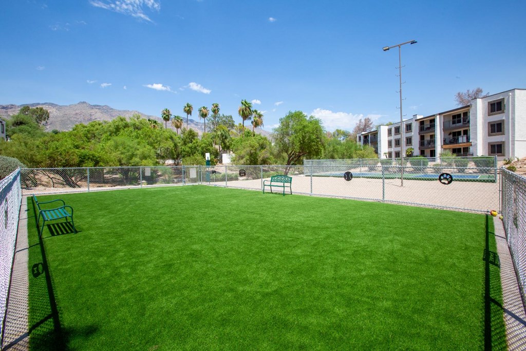 A tennis court with a green bench and a fence.