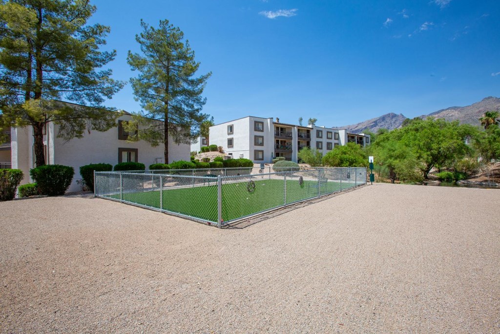 A tennis court surrounded by a fence and buildings.