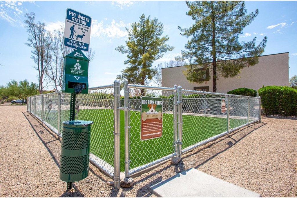 A sign for a pet waste station is in front of a chain link fence.