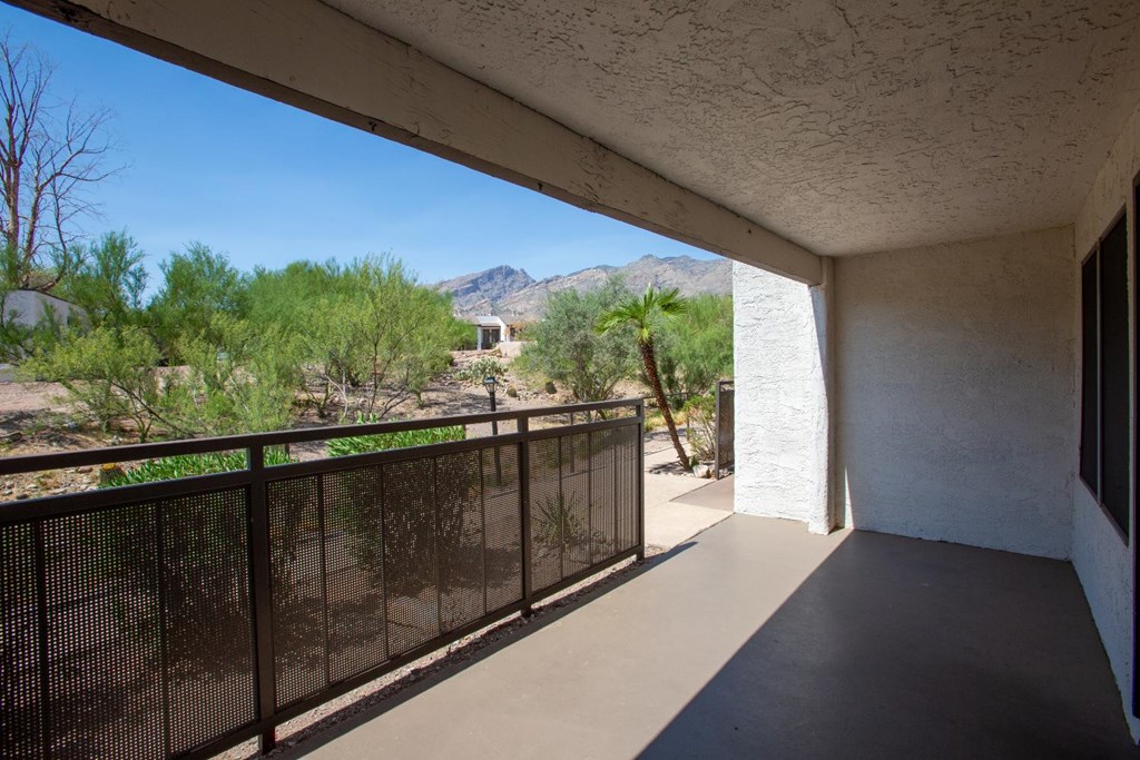 A balcony with a black railing overlooks a desert landscape.