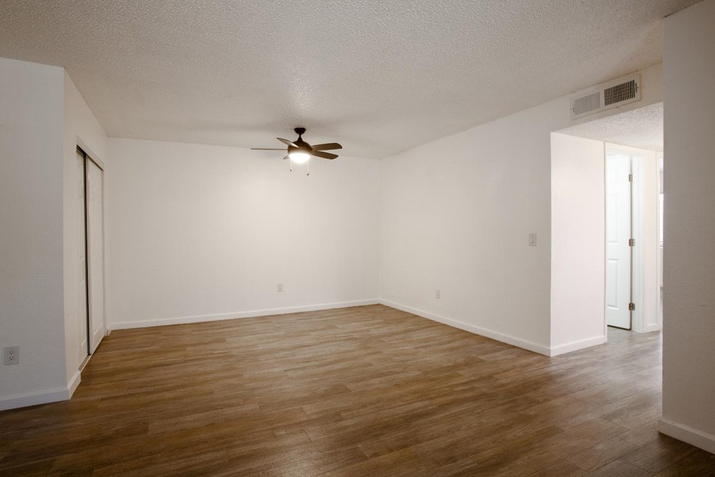 A room with a ceiling fan and wooden flooring.