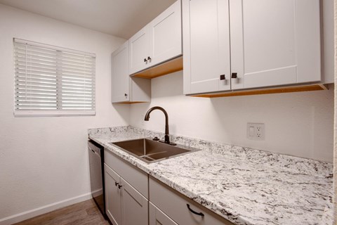 A kitchen with white cabinets and a marble countertop.
