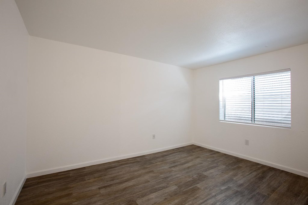 A room with wooden flooring and a window with blinds.