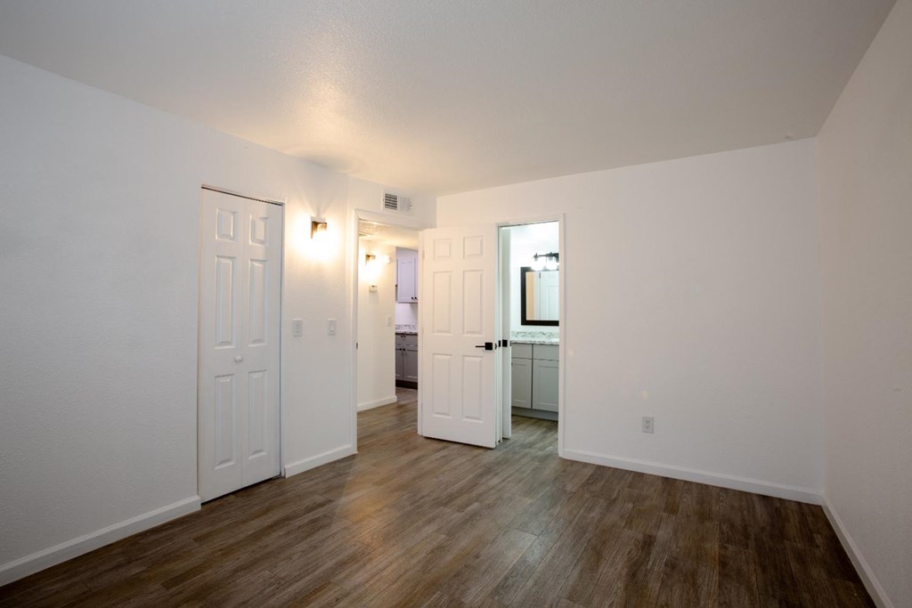 A room with white walls and wooden flooring with two doors.