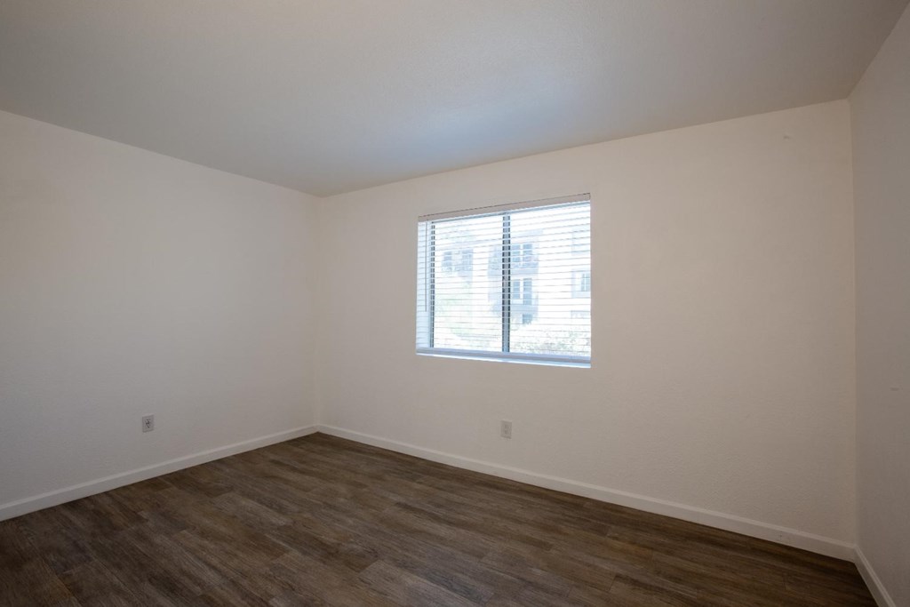 A room with a window and wooden flooring.