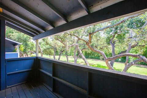 A balcony with a view of trees and a building.