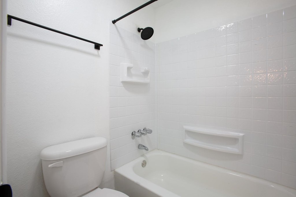 A white toilet sits next to a white bathtub in a bathroom.