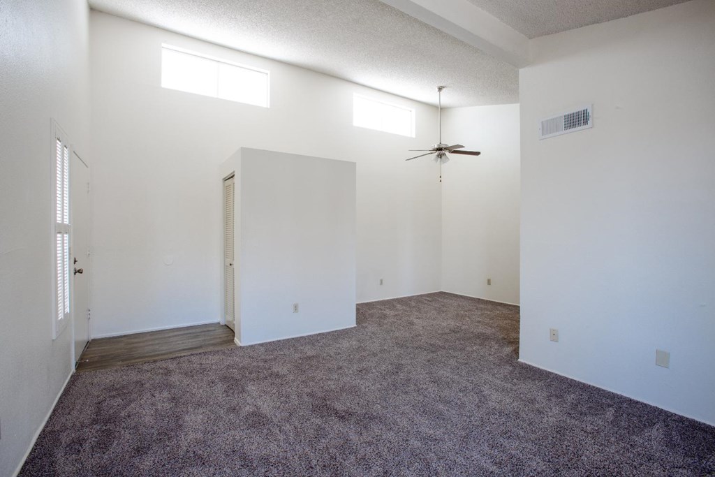 A room with a ceiling fan and carpeted floor.