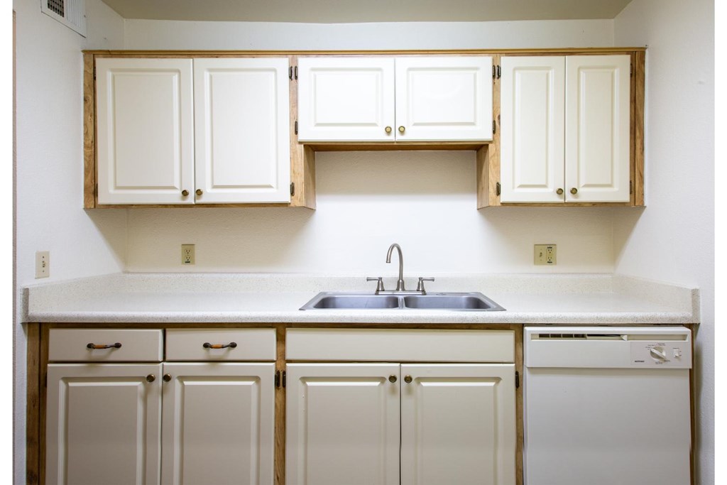 A kitchen with white cabinets and a white dishwasher.