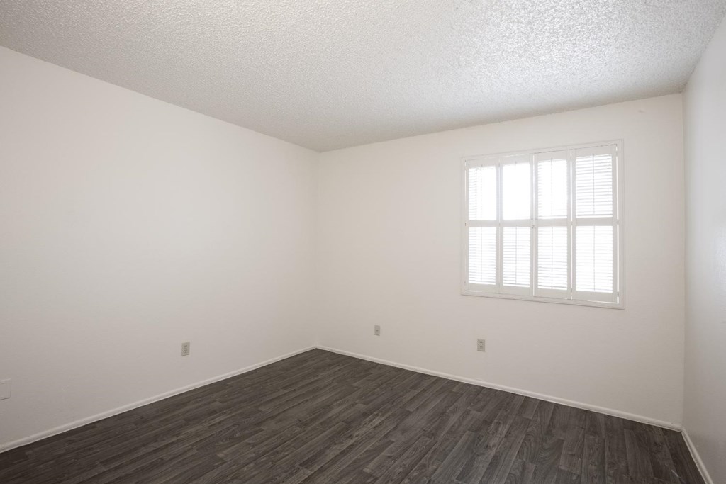 A room with a window and wooden flooring.