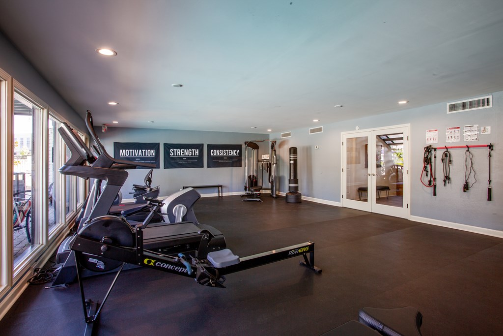 A gym with a row of exercise bikes and a sign that says "Motivation Strength Consistency".