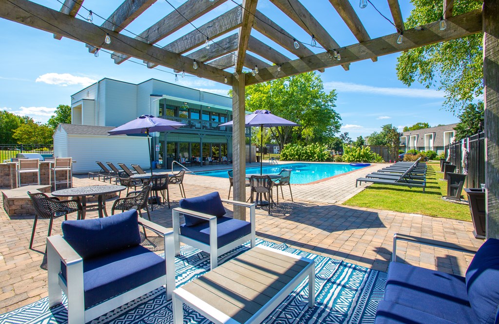 A patio with blue cushions and a pool in the background.