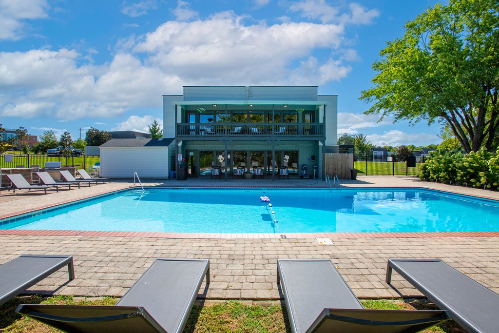 A swimming pool with lounge chairs and a building in the background.