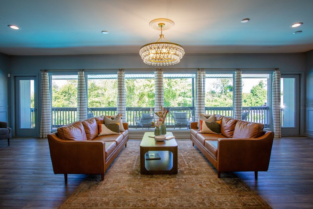 A living room with brown leather couches and a chandelier.