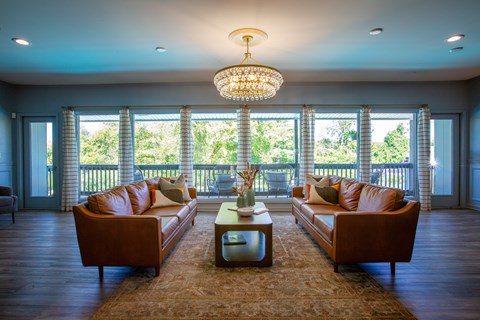 A living room with brown leather couches and a chandelier.