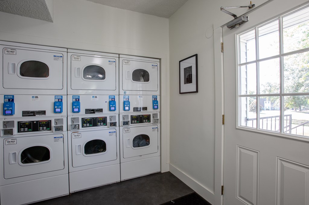 A row of washing machines are lined up in a laundry room.