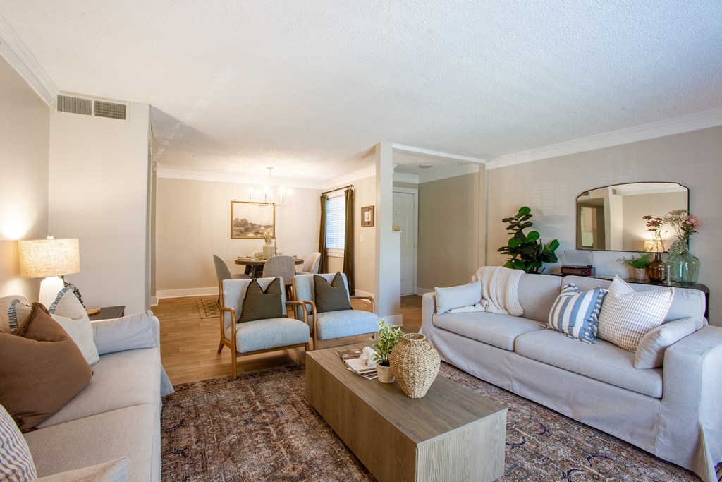 A living room with a grey couch, a wooden coffee table, and a large mirror on the wall.
