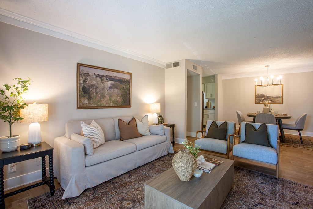 A living room with a couch, chairs, and a painting on the wall.