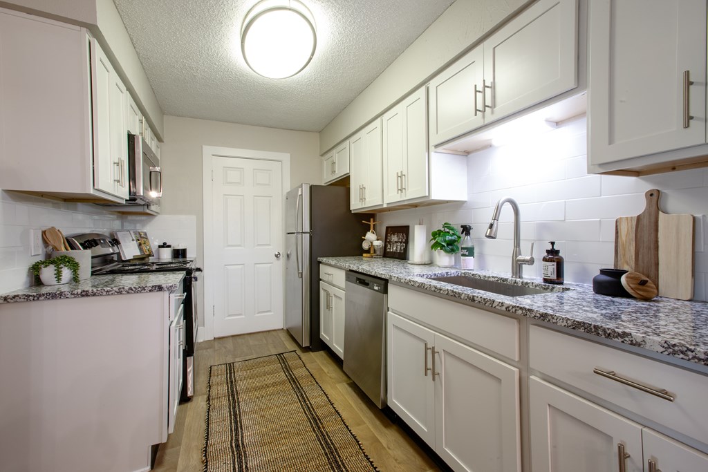 A kitchen with white cabinets and a granite countertop.