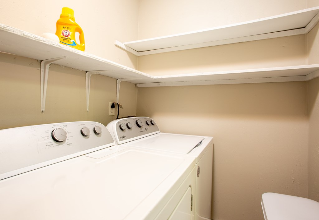 A yellow bottle of detergent is on top of a white washing machine.
