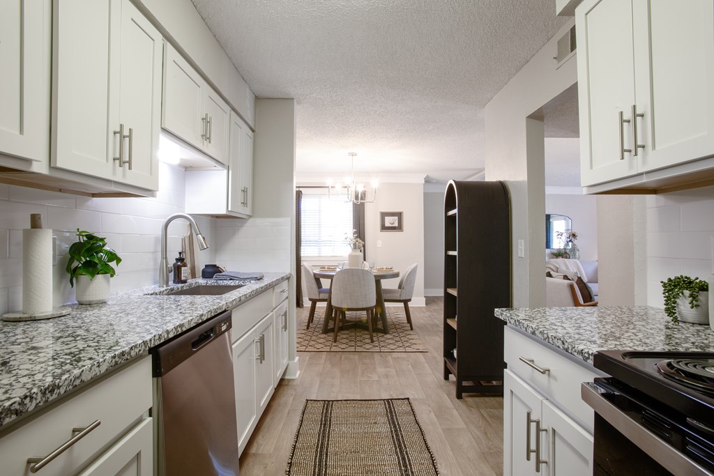 A kitchen with white cabinets and a marble countertop.