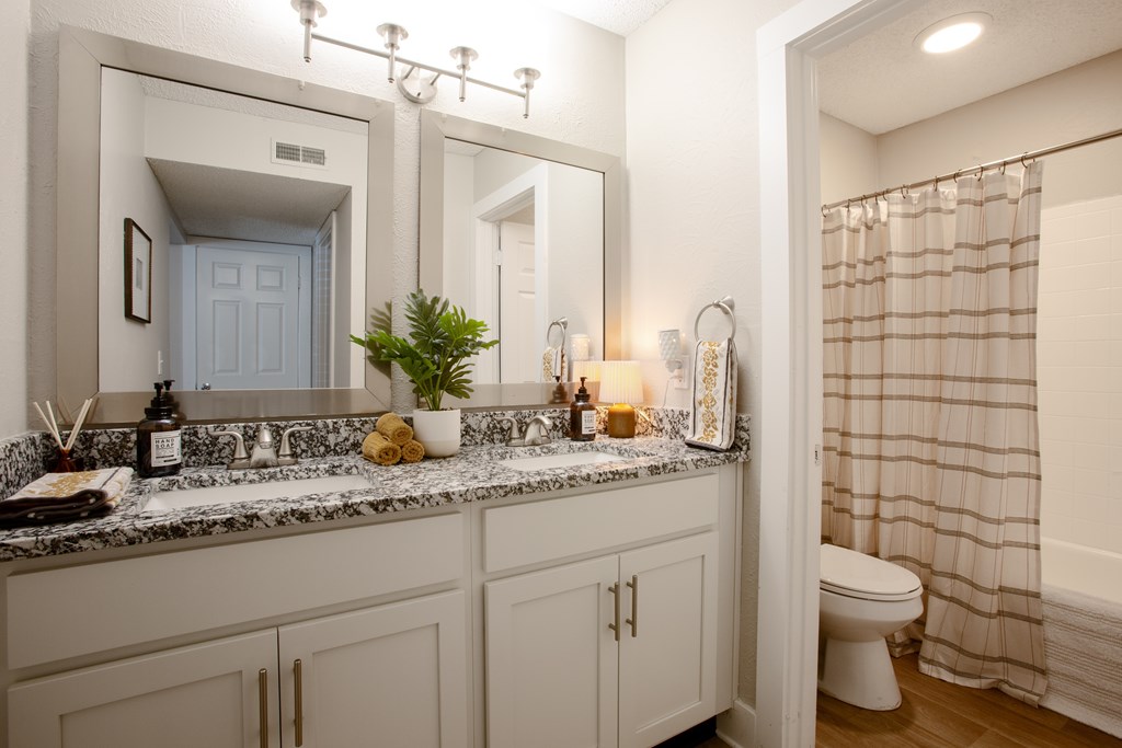 A bathroom with a marble countertop and white cabinets.