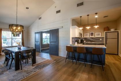 A modern kitchen with dark wood floors and a dining table with chairs.