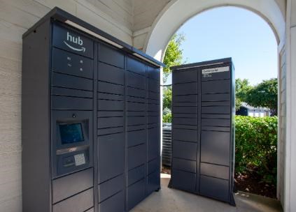 Two dark grey Amazon Hub kiosks are situated under an arched structure.