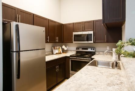 A kitchen with a refrigerator, microwave, oven, and sink.