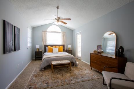 A bedroom with a bed, dresser, and a ceiling fan.