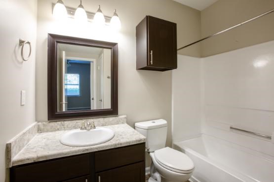 A bathroom with a toilet, sink, and mirror.