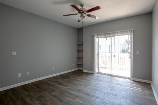 A room with a ceiling fan and sliding glass doors.