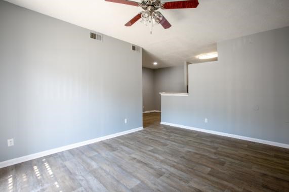 A room with a ceiling fan and wood flooring.