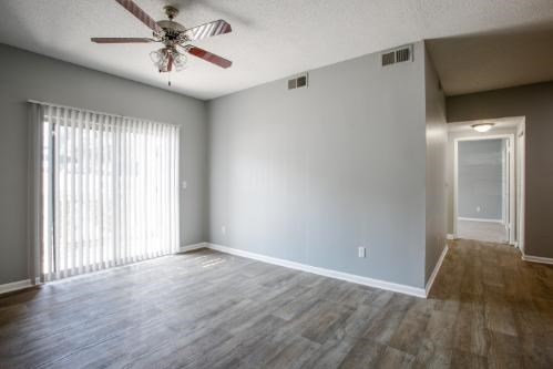 A room with a ceiling fan and wooden flooring.