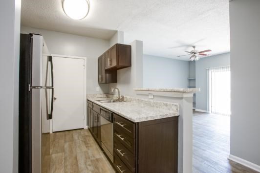 A kitchen with a white counter top and wooden cabinets.