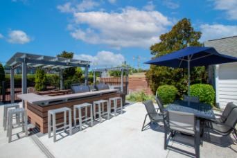 A patio with a bar and seating area under a blue umbrella.