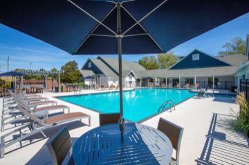 A pool area with sun loungers and a table under a large umbrella.