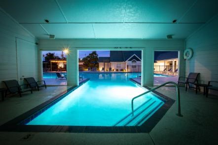 A swimming pool inside a building with lights on.