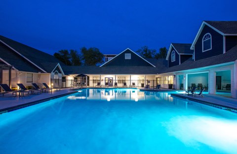 A large swimming pool lit up with blue lights at night.