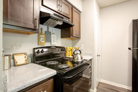 A kitchen with a black stove top oven and wooden cabinets.