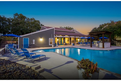 A poolside lounge area with chairs and a building in the background.