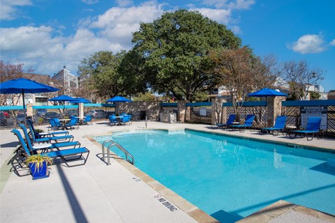 A pool surrounded by blue chairs and umbrellas.