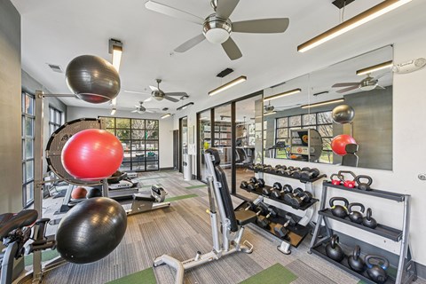 A gym with a variety of equipment including weights and exercise balls.